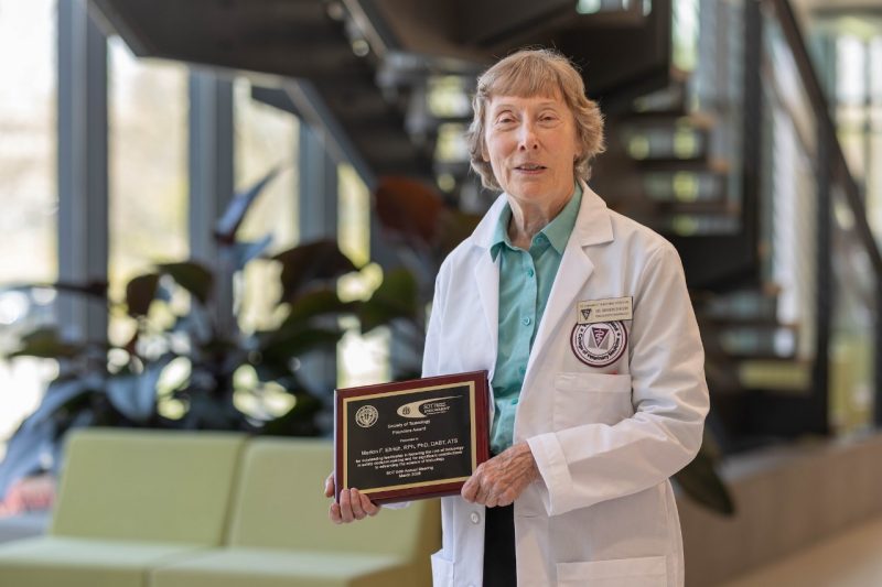 Dr. Marion Ehrich (at center) posing with a plaque in a white lab coat